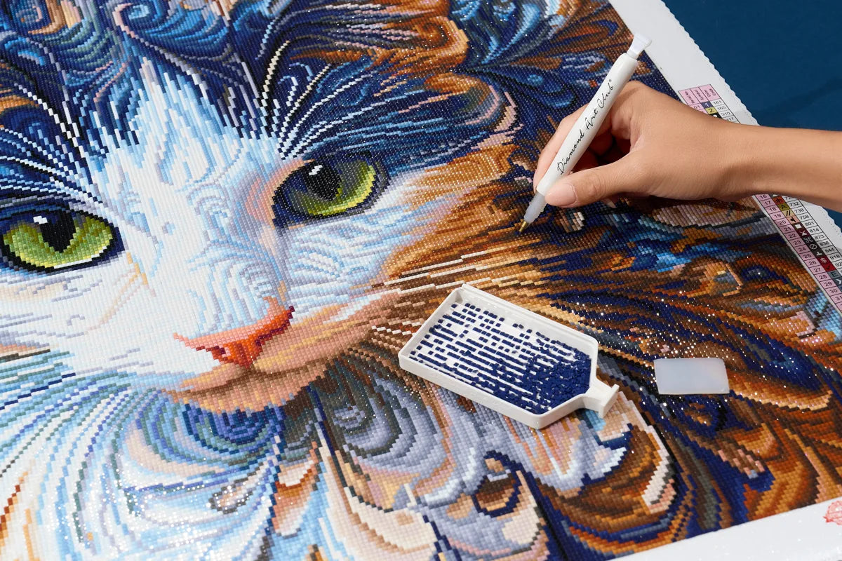Hand placing diamonds on A Cat Named Dollie Joy by Peggy Collins, with a diamond painting pen and tray.