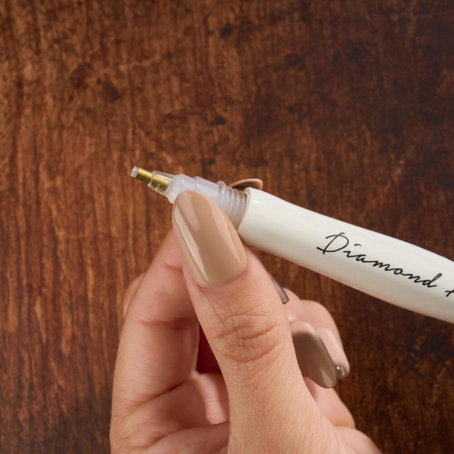 The tip of a white Twist & Pick diamond painting pen.