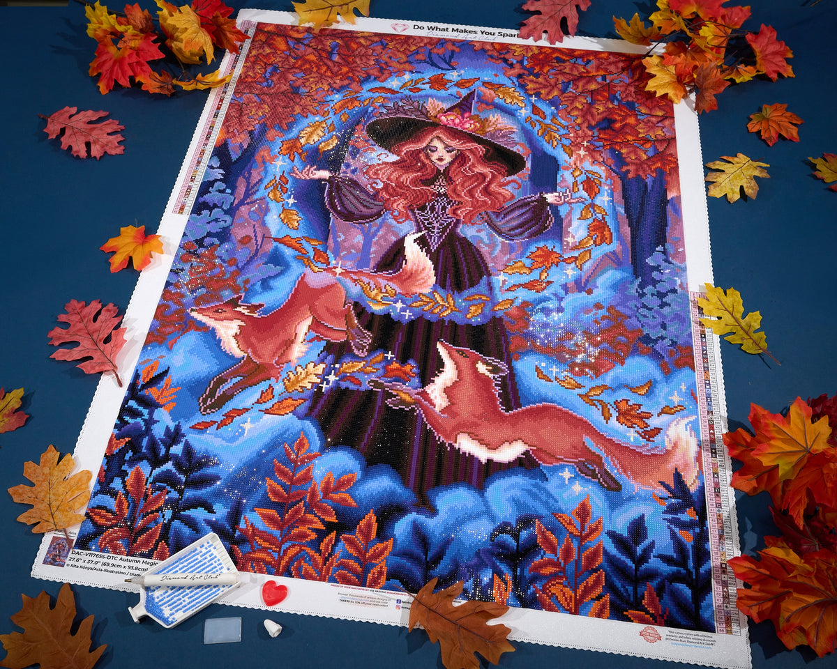 Autumn Magic diamond painting featuring a witch and two foxes, photographed with autumn leaves.