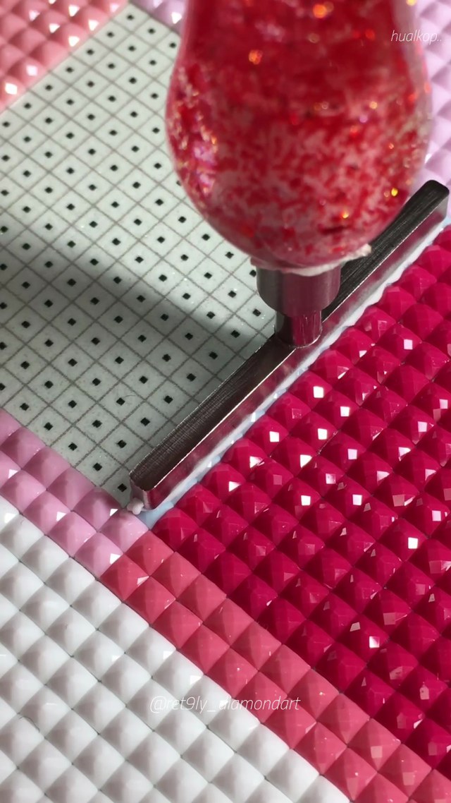 A red glitter applicator placing a neat row of square diamonds beside sparkling pink and blue rows