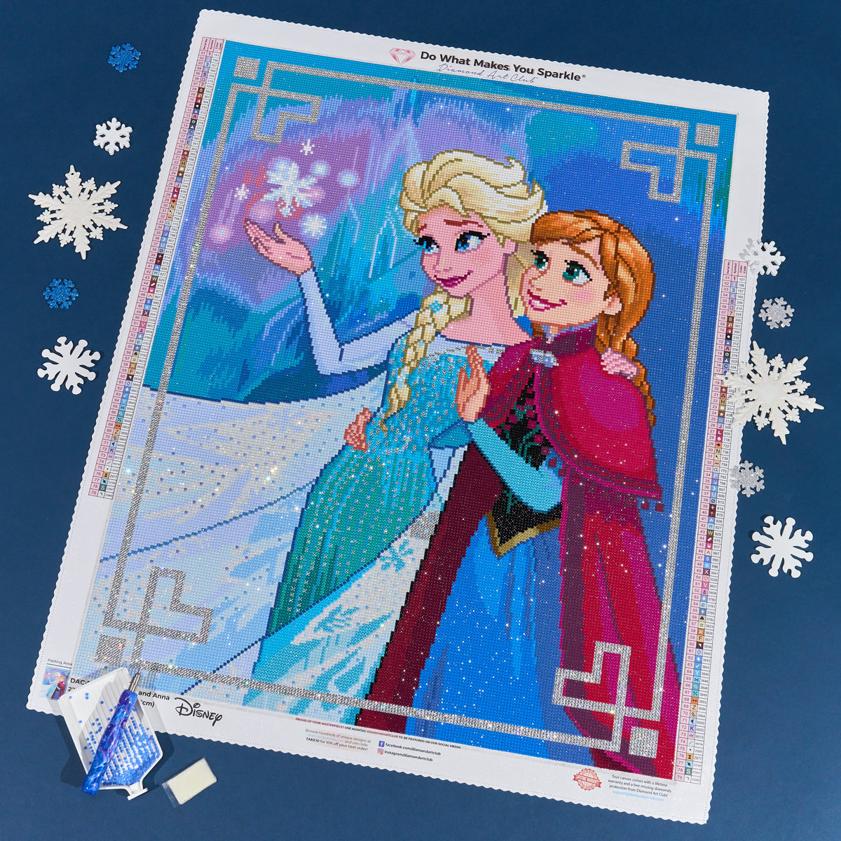 Elsa and Anna diamond painting, photographed in full on a navy blue background with snowflakes.